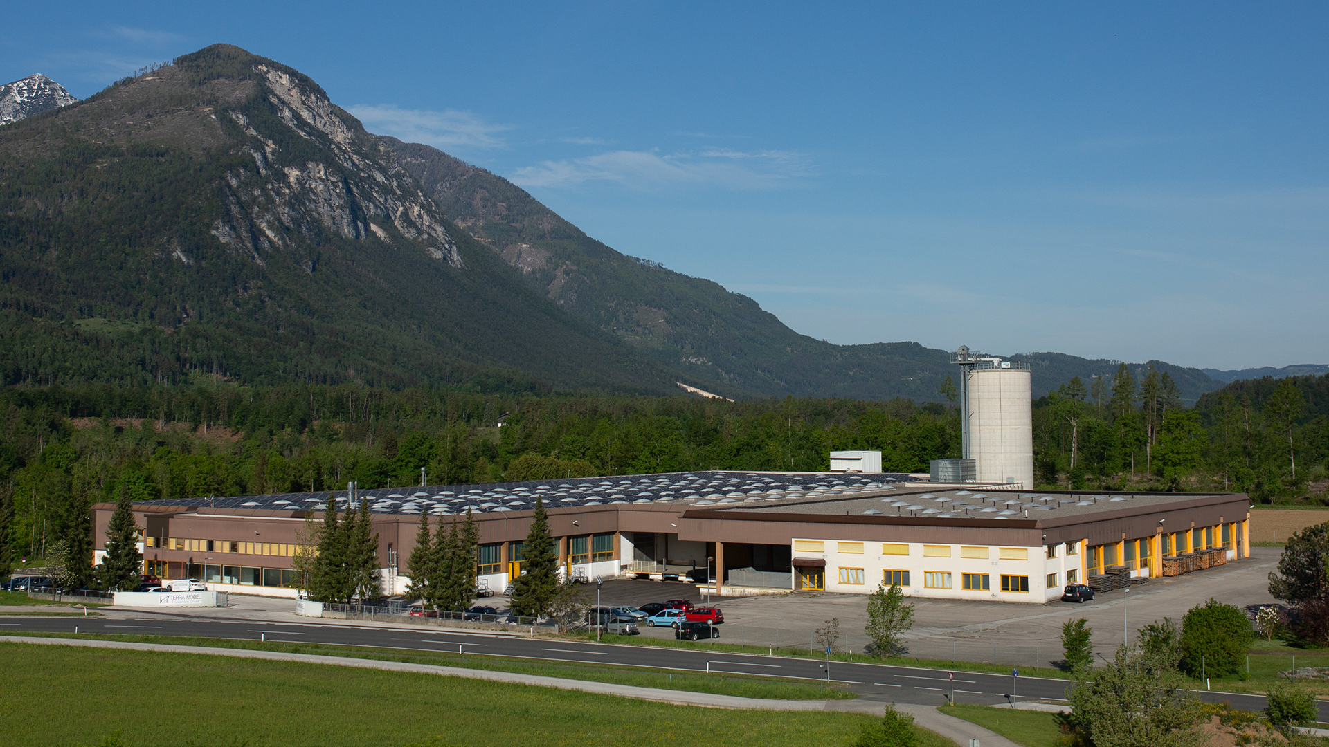 Tischlerei Gebäude vor Berglandschaft mit Wald und blauem Himmel