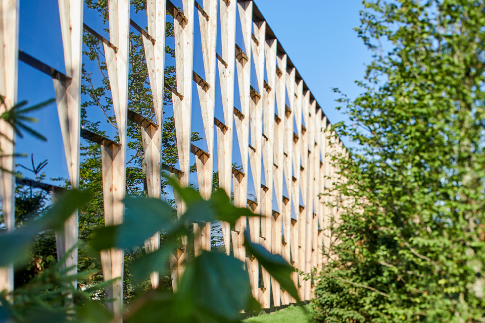 Detailansicht von Fassade mit vertikalen Holzlamellen und blauem Himmel