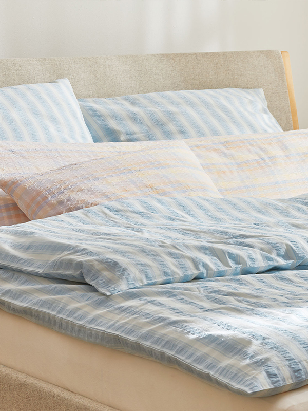 Blau weiß gestreifte Bettwäsche im Bett