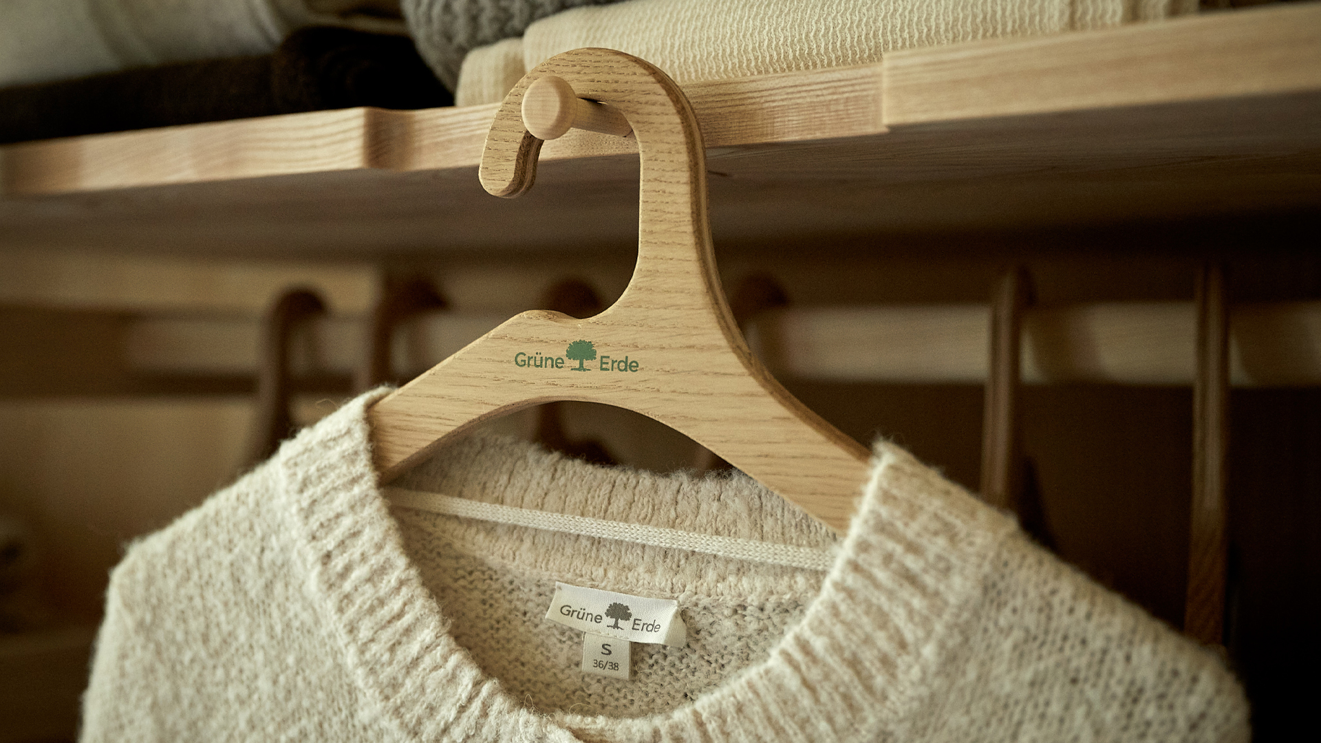 Heller Strickpullover hängt ordentlich auf Holzkleiderbügel
