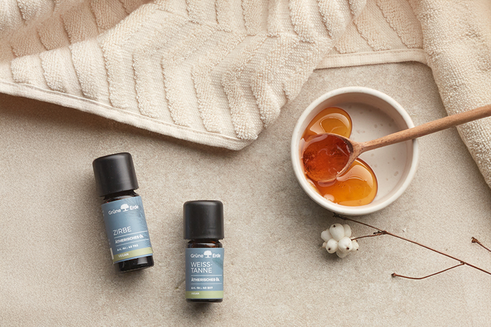 Zwei ätherische Öle neben Honig und Handtuch natürliche Hautpflege