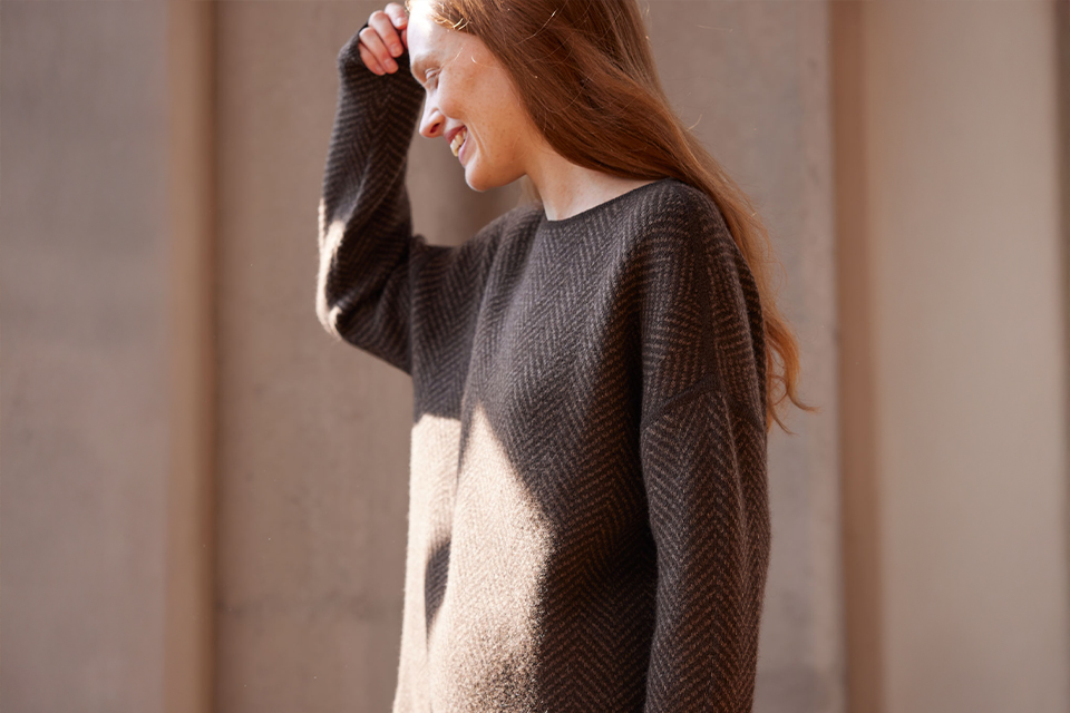 Frau lächelt in einem braunen Pullover