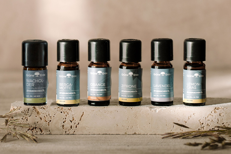 Sechs verschiedenfarbige Aromaöle nebeneinander auf einem Stein