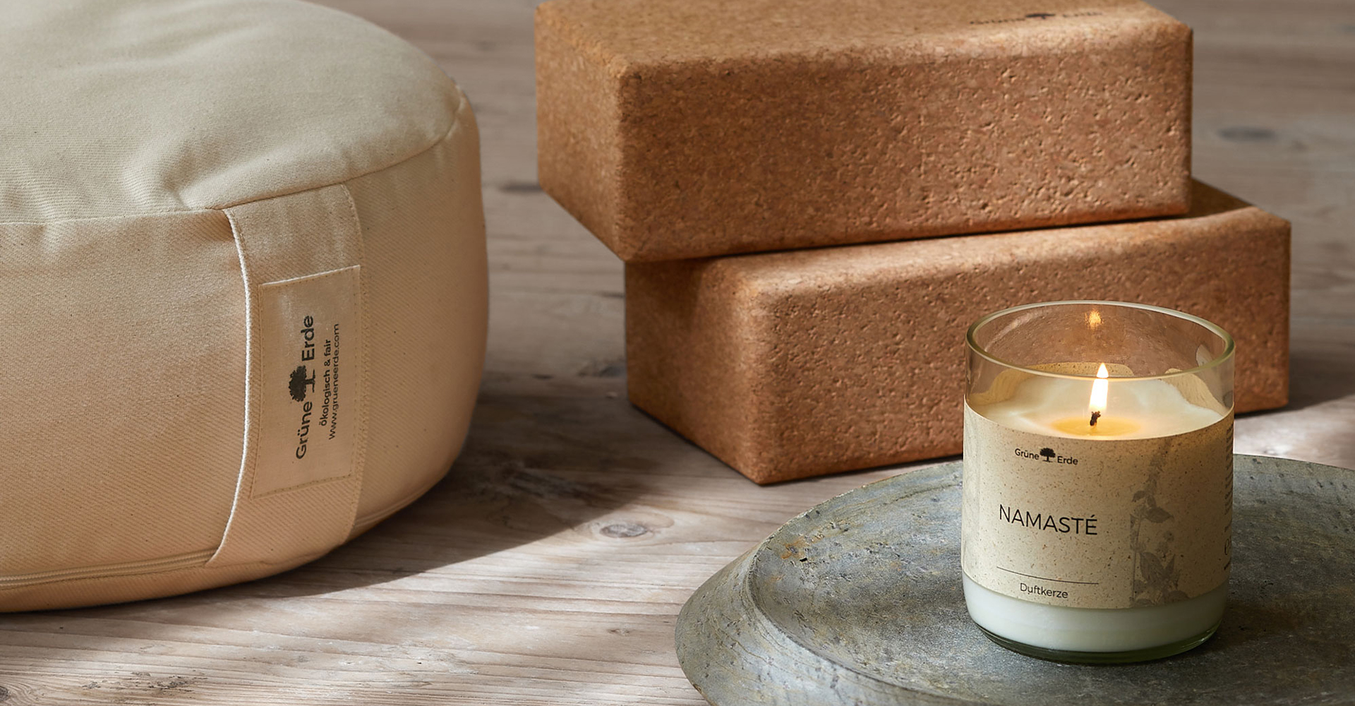 Yogakissen Korkblöcke und brennende Duftkerze auf Tablett in ruhiger Umgebung