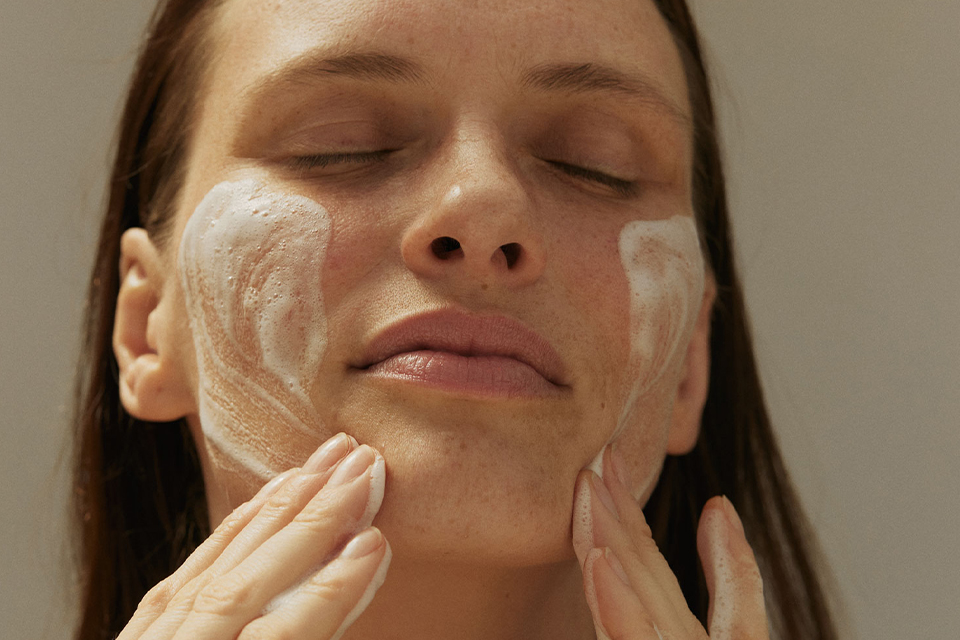 Frau trägt Gesichtsmaske auf und genießt entspannende Hautpflege Routine
