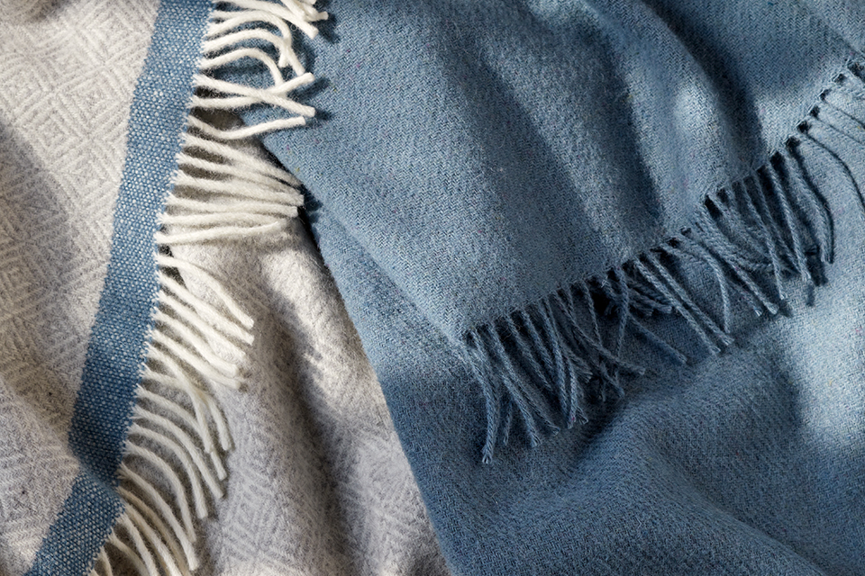 Eine blaugraue Wohndecke und eine blaue Wohndecke liegen übereinander