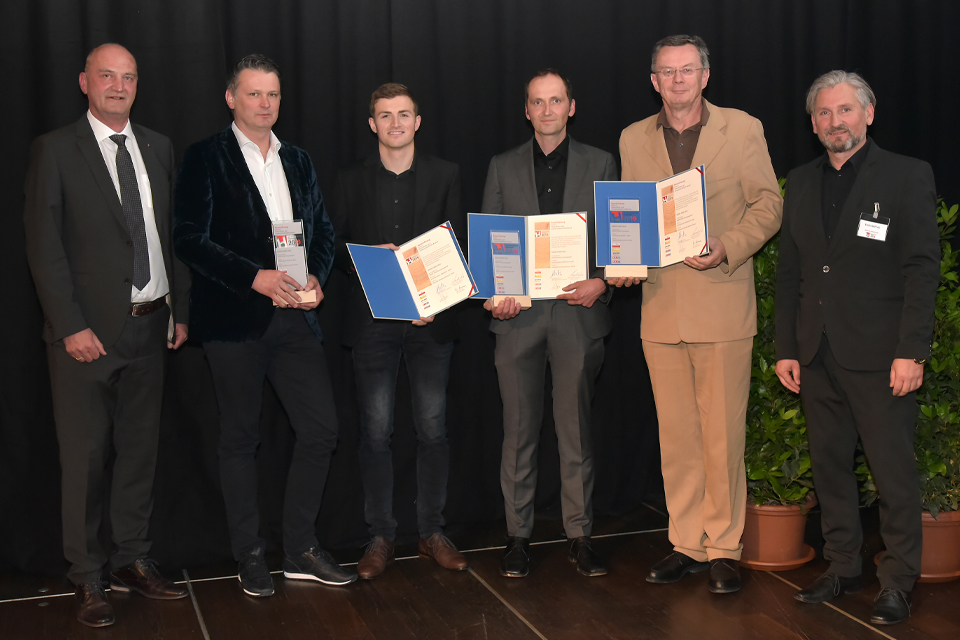 Gruppe von Männern steht auf Bühne mit  Auszeichnung in den Händen