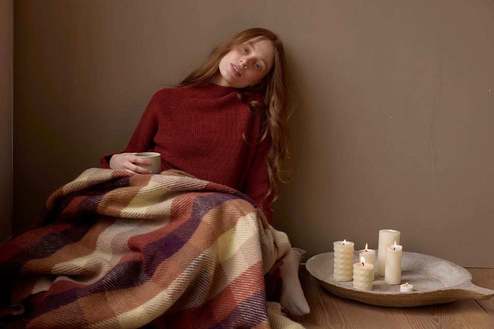 Frau ruht sich eingehüllt in Decke in ruhiger Umgebung aus