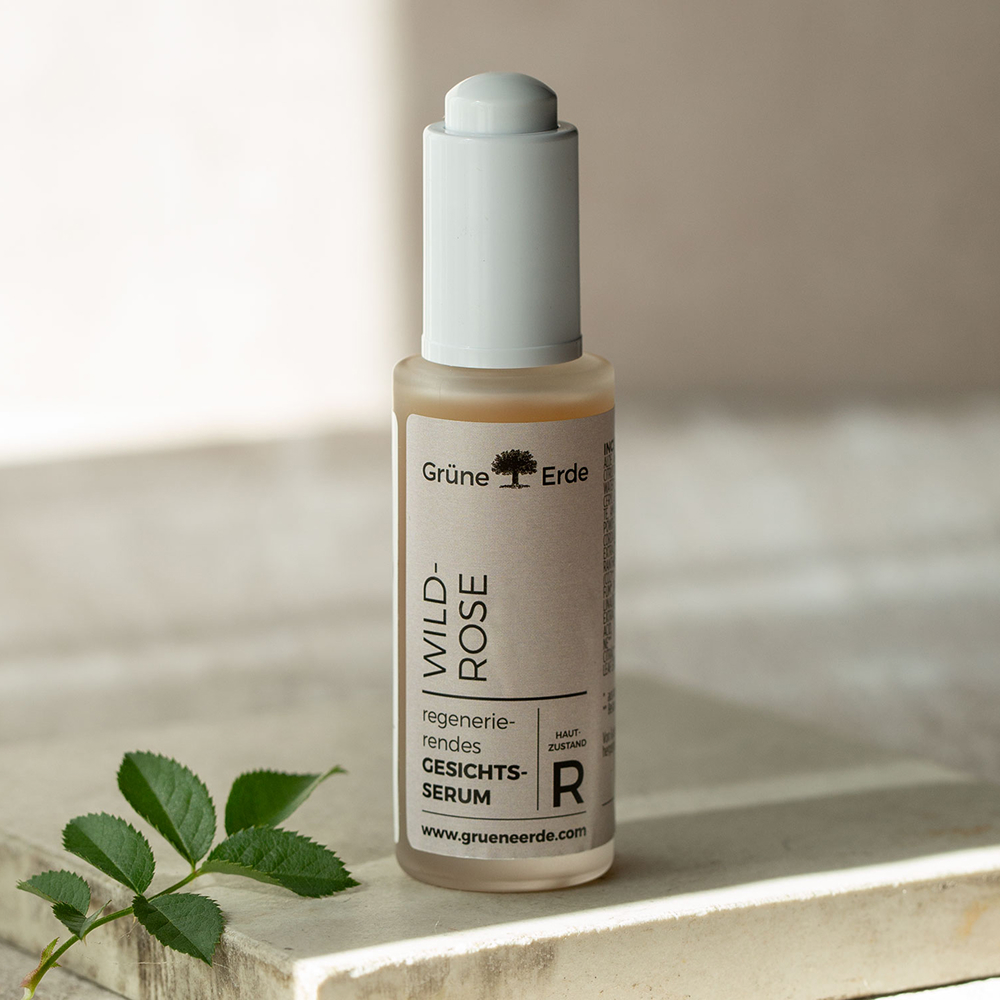 Fläschchen vom Gesichtsserum Wildrose mit einem dekorativen Zweig