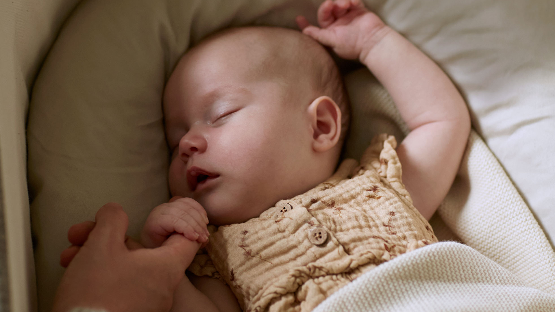 Baby schläft und hält den Finder eines Erwachsenen