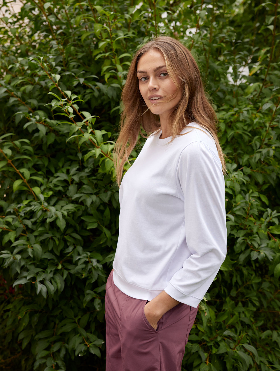 rau trägt weißes Langarmshirt und violette Hose in natürlicher Umgebung