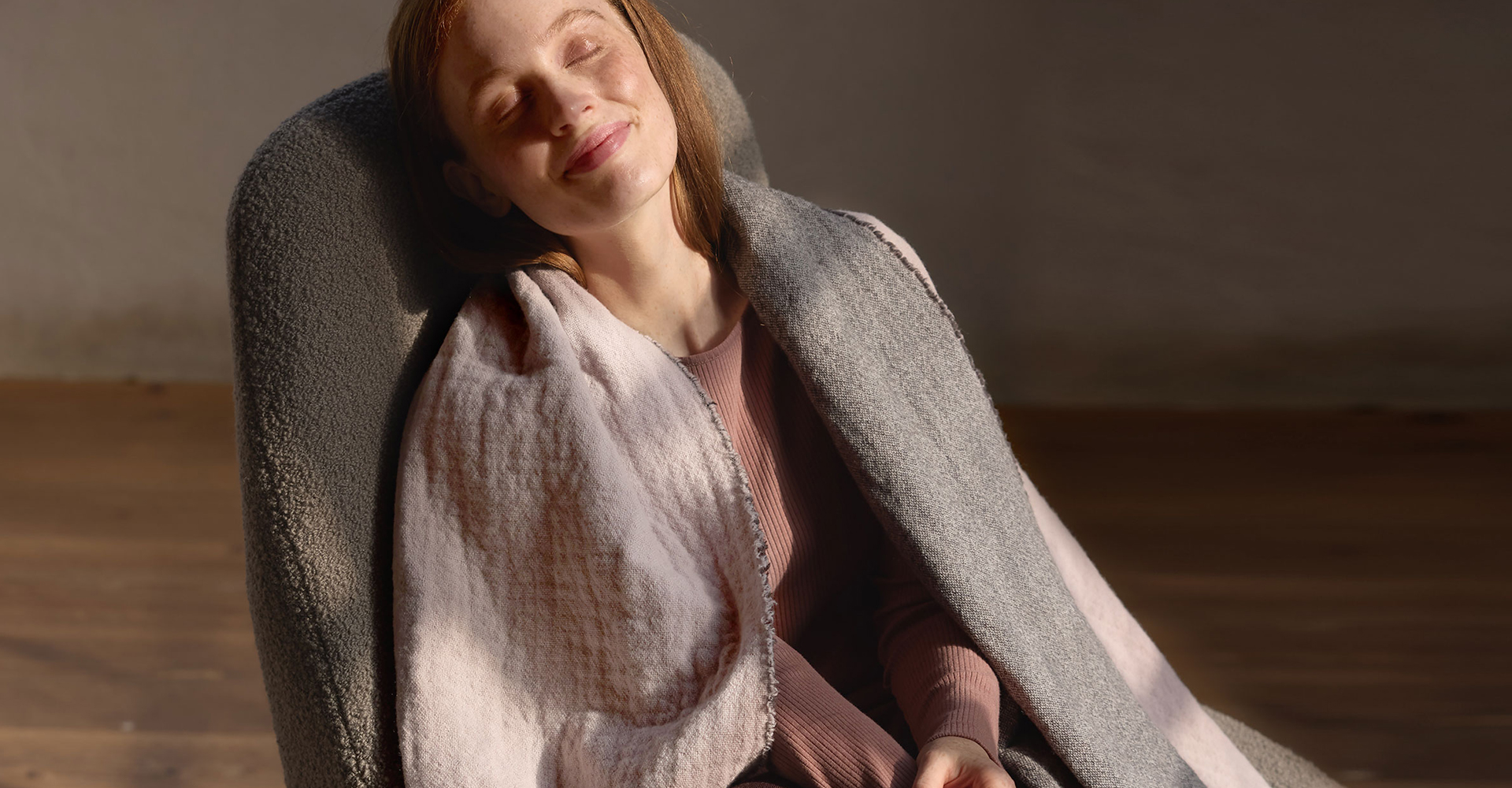 Frau in Wohndecke gehüllt auf Sofa