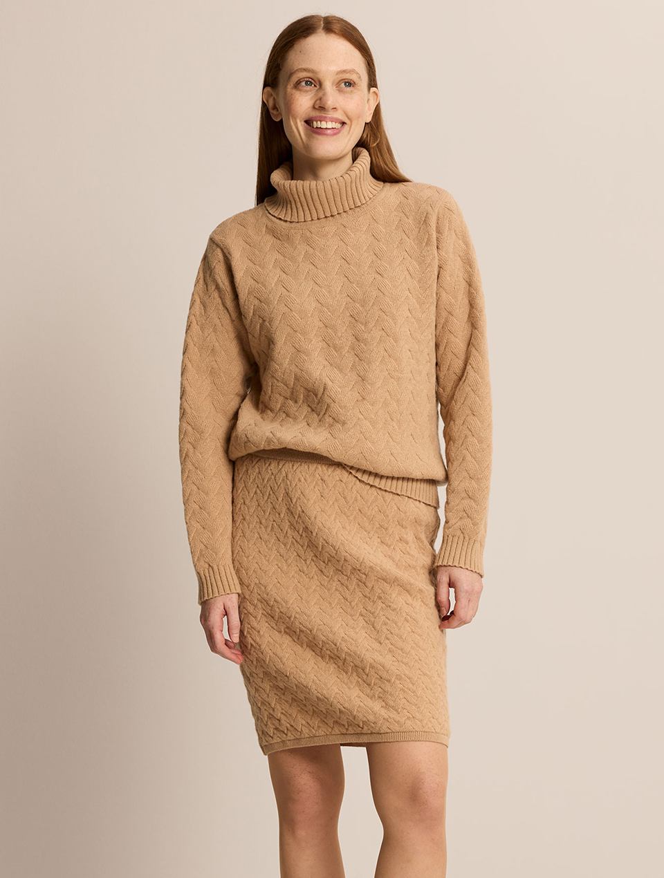 Lächelnde Frau trägt ein Set aus einem Pulli und einem Rock