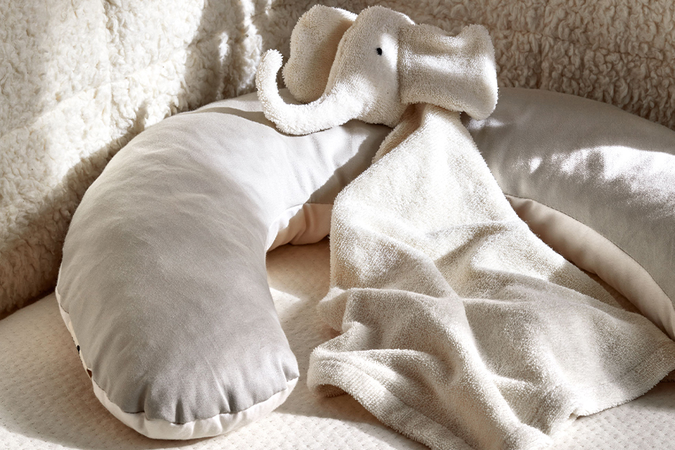 Nackenkissen und Stoffelefant in einem Kinderbett