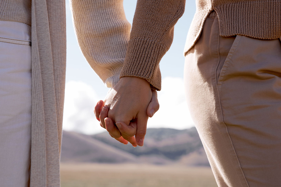 Zwei Menschen halten sich liebevoll an den Händen draußen