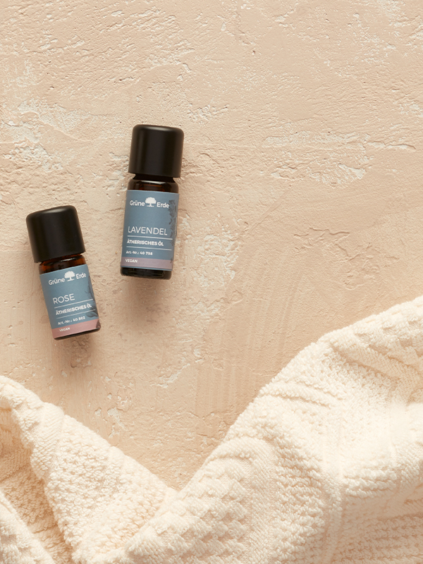 Ätherische Öle neben einem hellen Tuch arrangiert