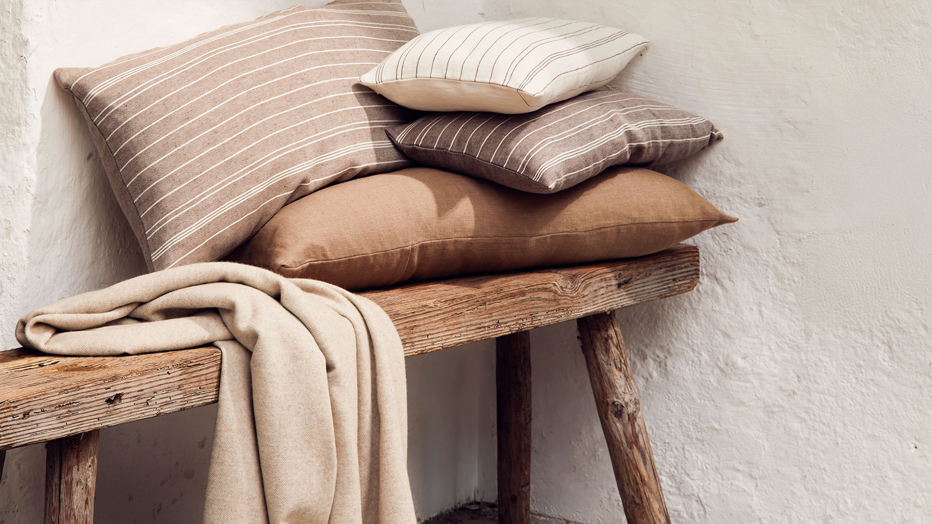 Zierkissen und Wohndecke auf dekorativer Holzbank