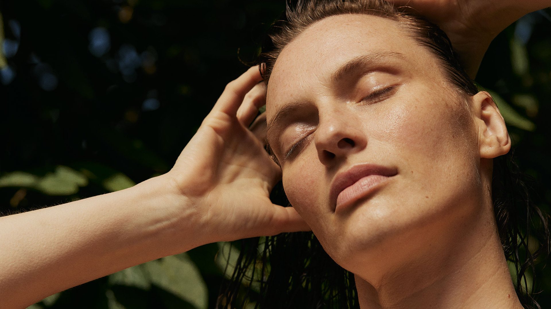 Frau fährt sich mit den Händen durch die nassen Haare