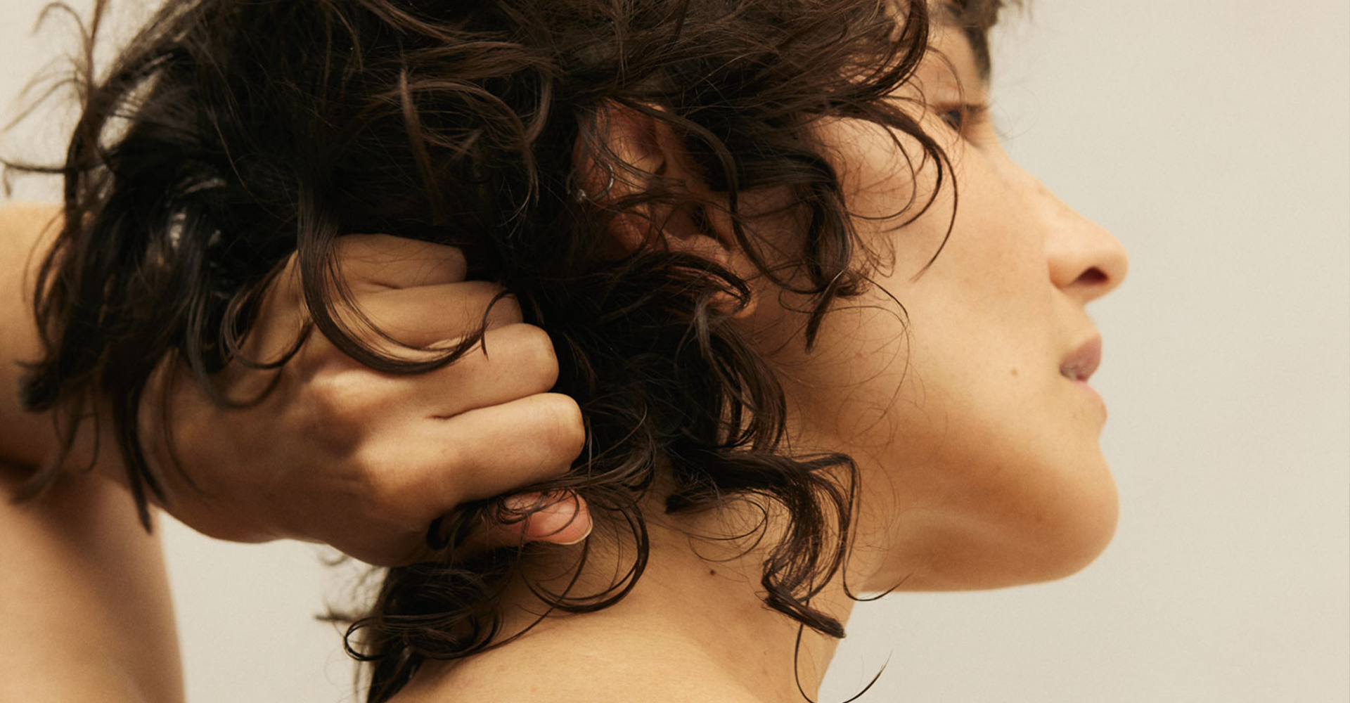 Frau mit Haaren in der Hand blickt in die Ferne