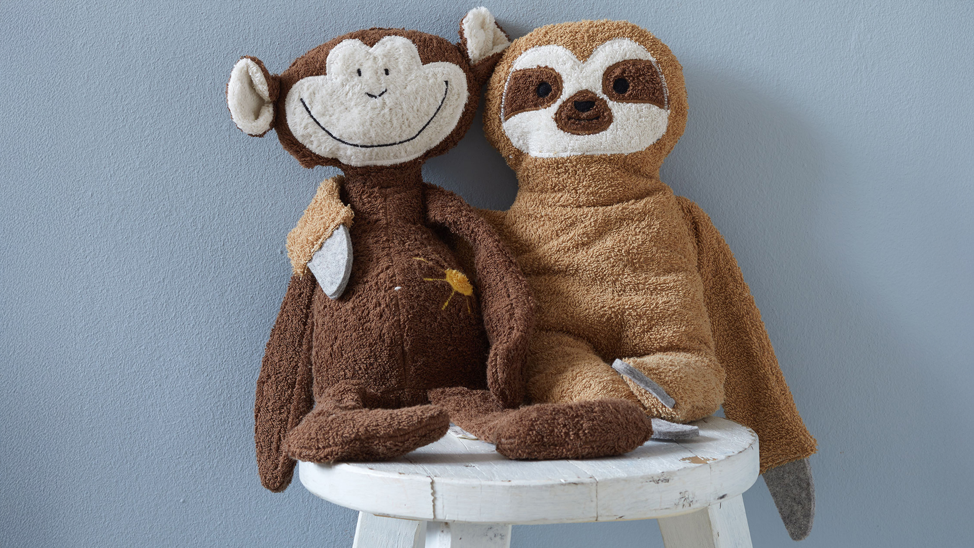 Kuscheltiere affe Abu und Faultier auf einem Stuhl sitzend