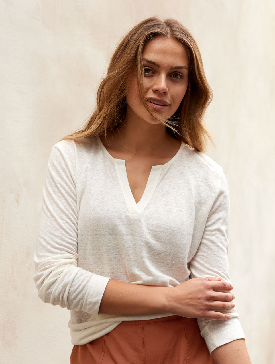 Frau trägt weißes Langarmshirt mit violetter Hose in natürlicher Umgebung