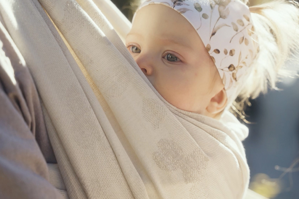 Baby hängt an einem sonnigen Tag im Tragetuch