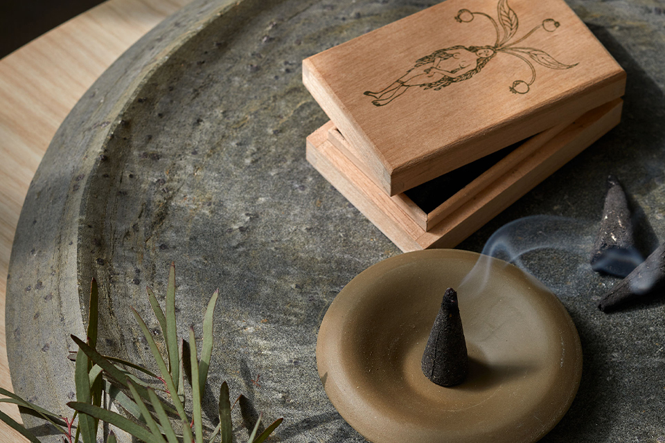 Räucherkegel auf Unterteller mit Holzbox und dekorativen Zweigen in ruhiger Umgebung