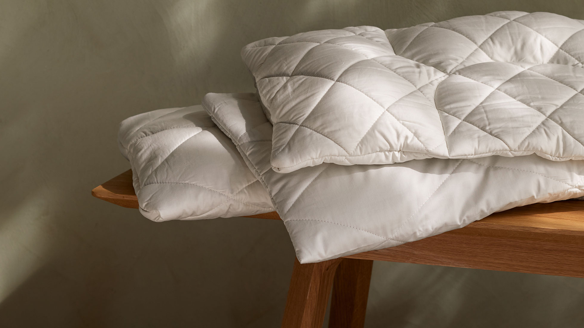 Drei hochwertige Kopfkissen auf einer Holzbank