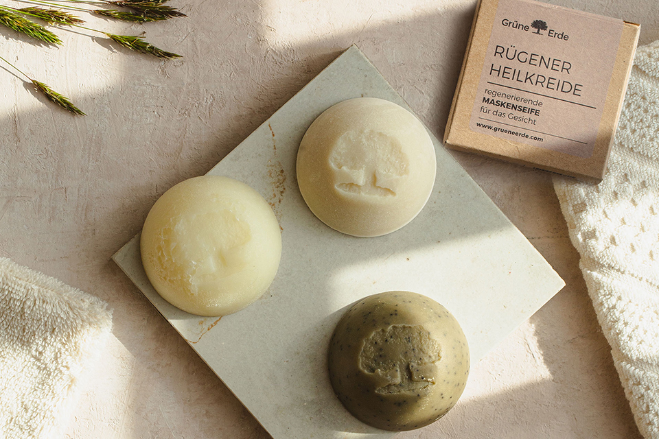 Zwei feste Seifen und ein Bürstchen mit einem dekorativen Blümchen