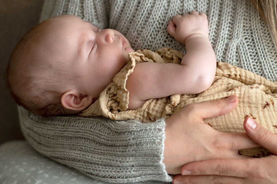 Baby schläft in den Armen seiner Mutter