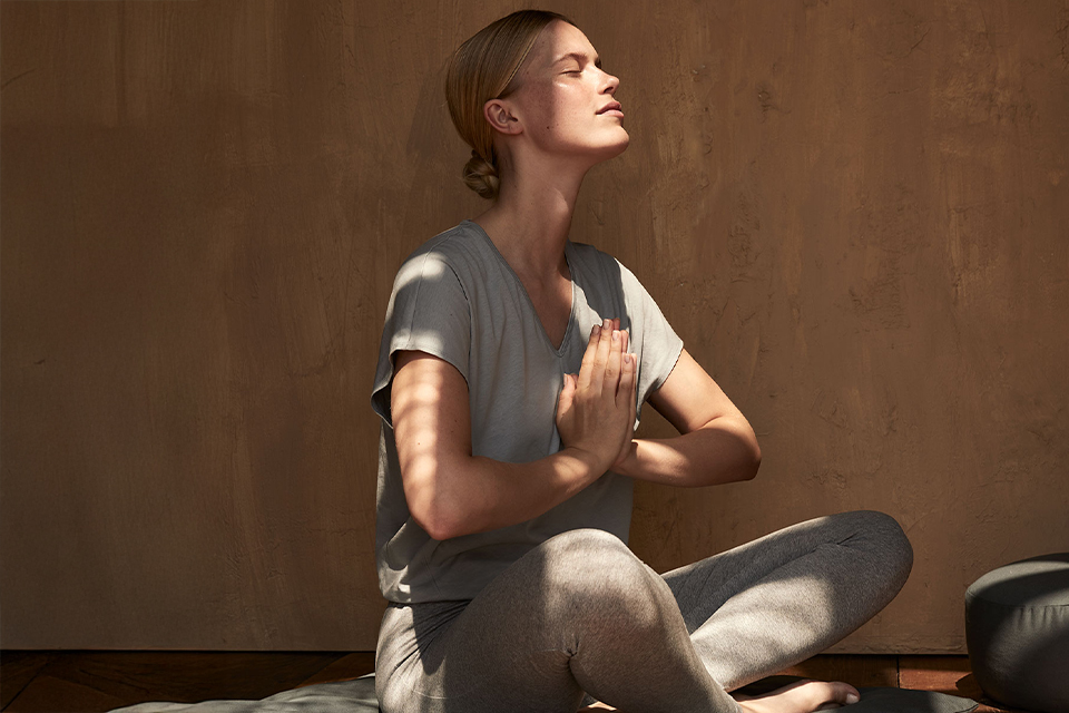Frau in Yogakleidung sitzt im Schneidersitz