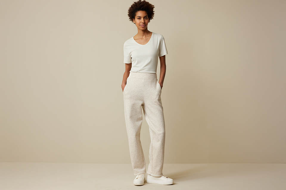 Ganzkörperaufnahme Frau in schlichter ungefärbter Kleidung stehend