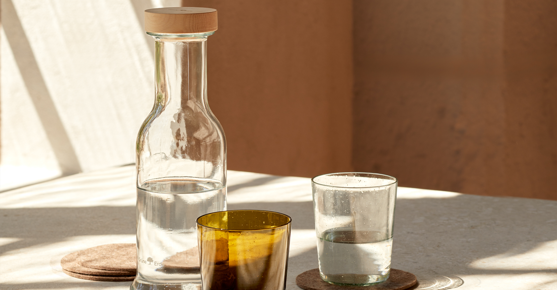 Eine Karaffe und ein dunkles Glas stehend auf einem Holztablett.