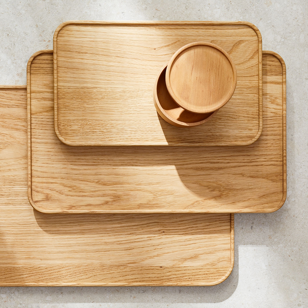 Drei Holztabletts der Größe nach gestapelt mit einer Holzschale in natürlichem Licht