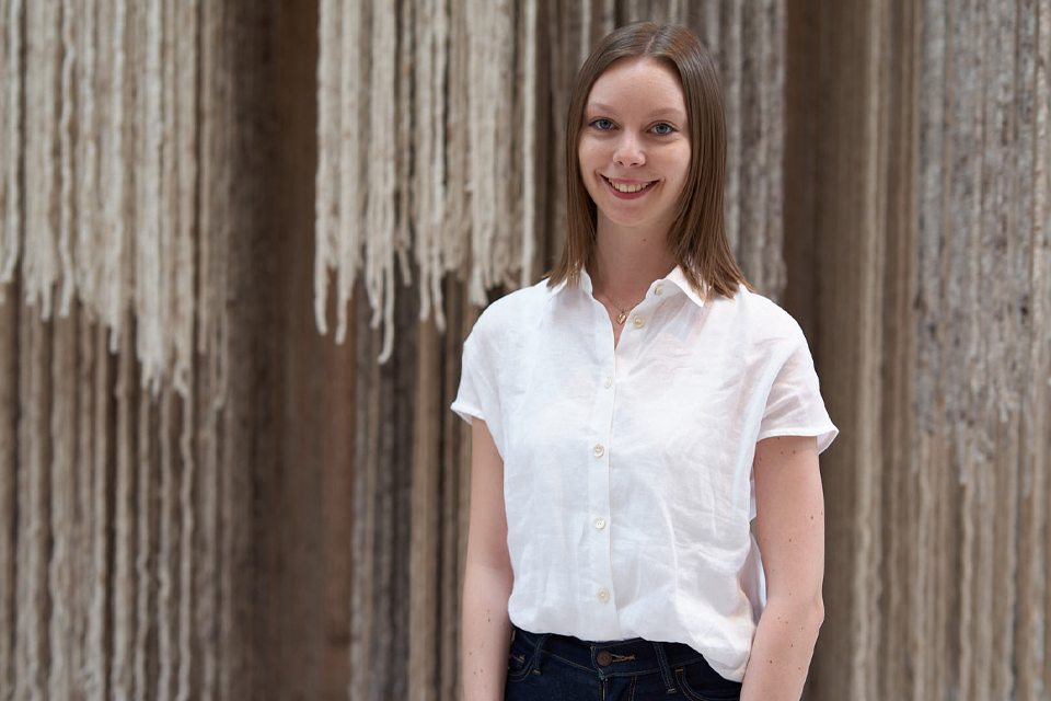 Junge Frau steht vor dekorativer Wand mit natürlicher Ausstrahlung