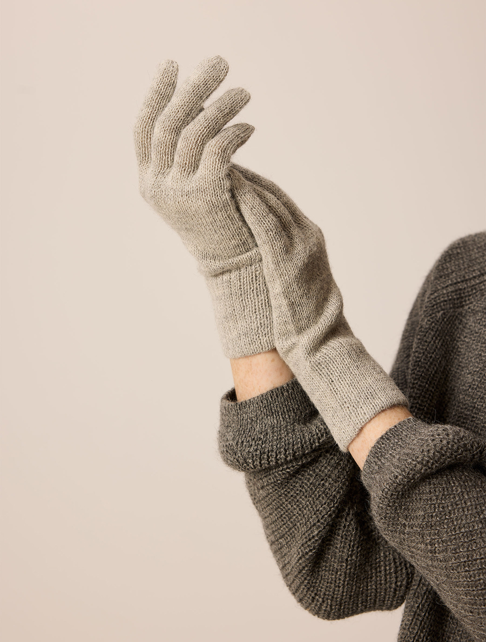 Hände tragen hellgraue Handschuhe