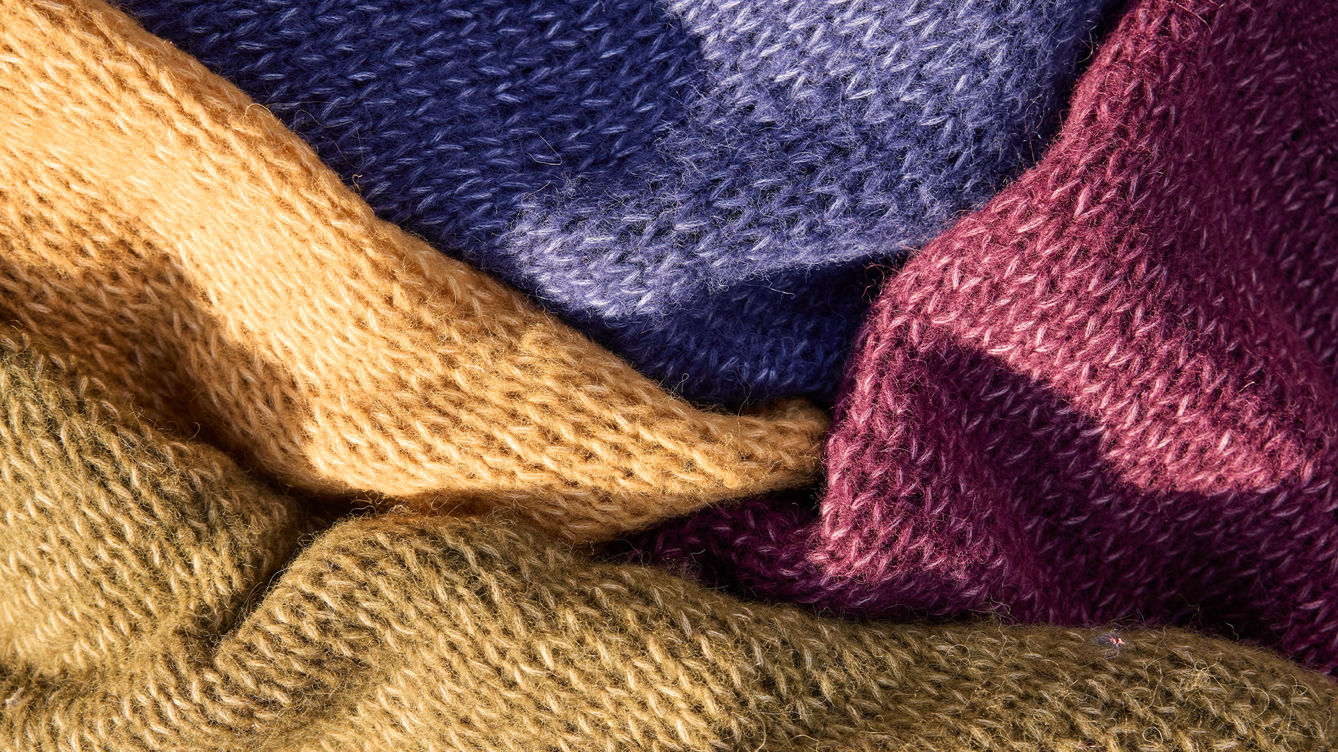 Bunte Stoffe in warmen Farben liegen weich übereinander