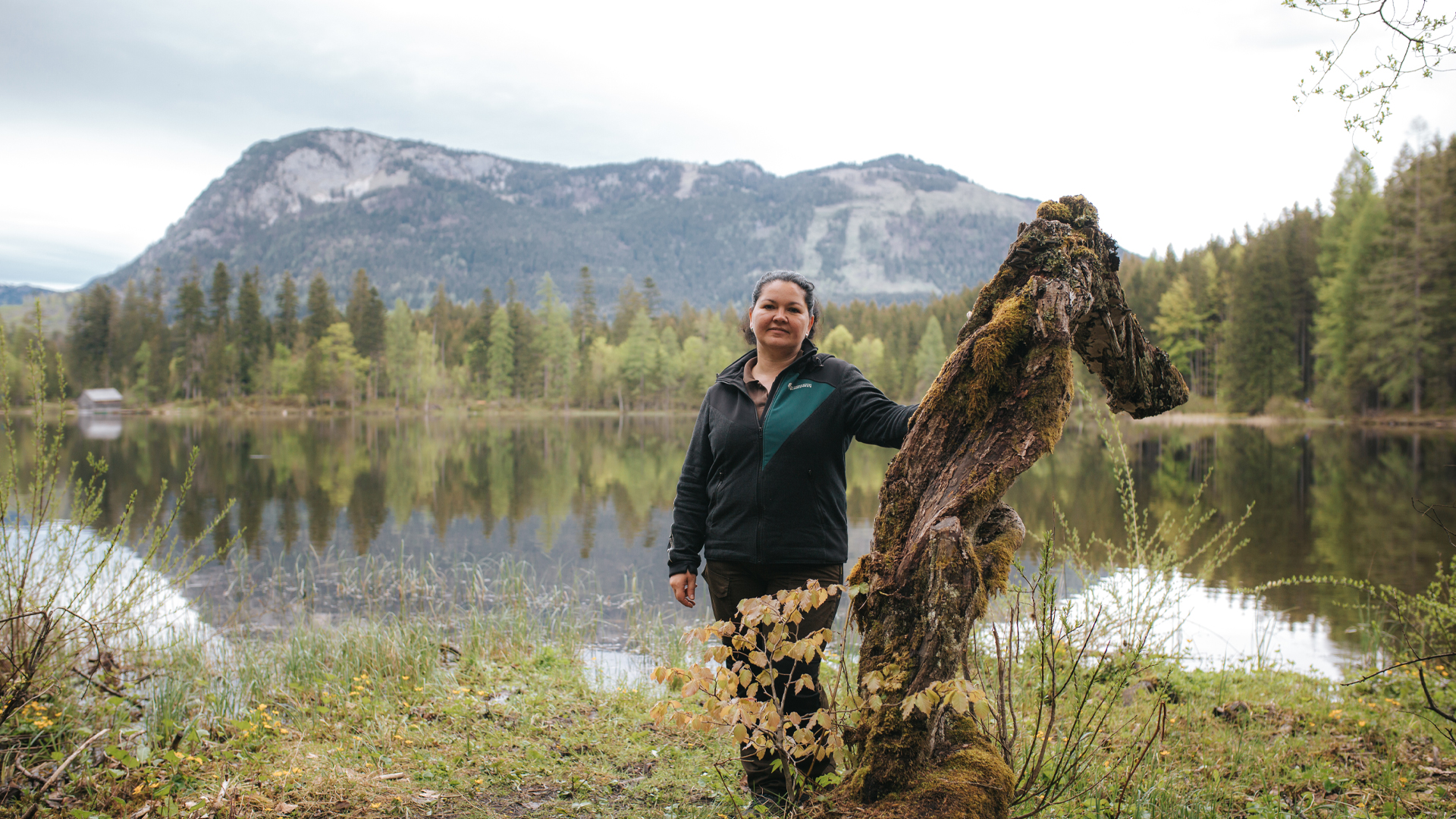 Frau steht am Ufer eines Sees