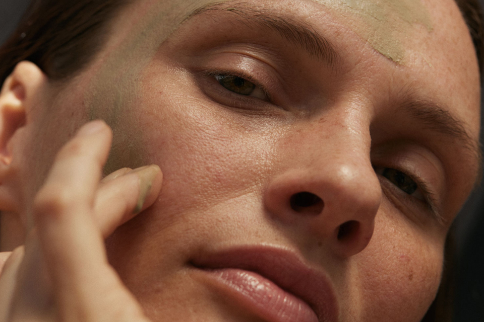 Frau mit geschlossenen Augen trägt Gesichtsmaske auf