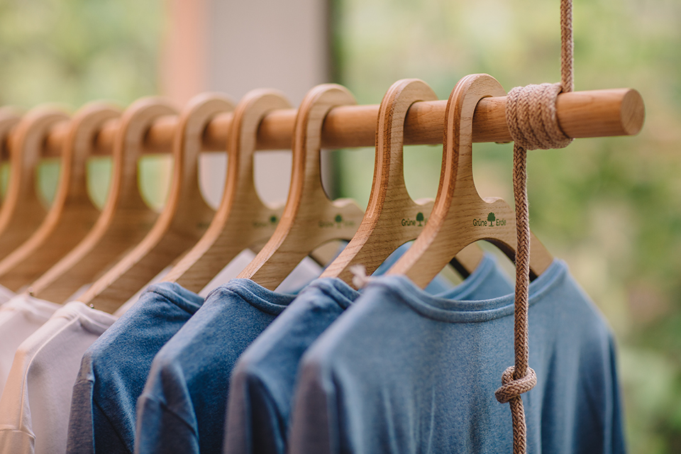 Kleidung auf Holzbügeln an Kleiderstange im Geschäft