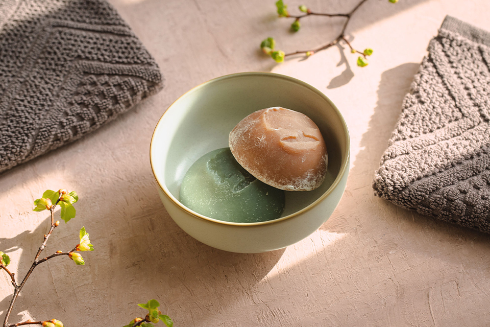 Eine grüne und eine braune feste Seife in einer Keramikschüssel