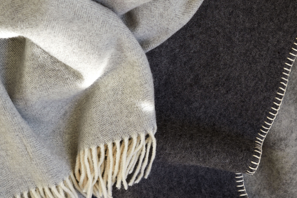 Eine helle und eine dunkle Lammwolldecke aufeinander liegend