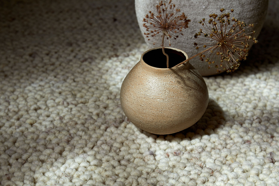 Naturteppich mit einer Keramikvase und dekorativen Blumen