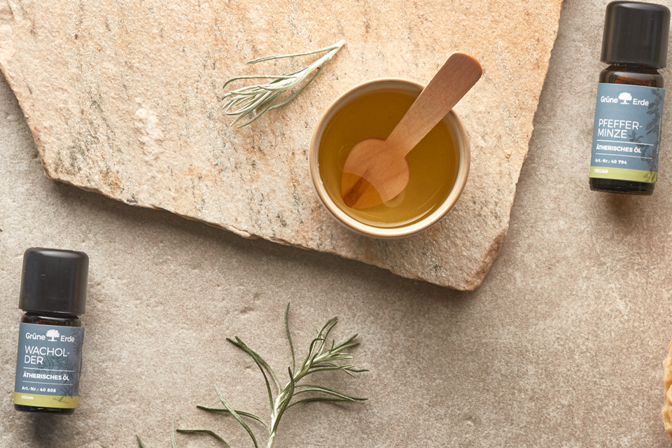 Schale mit Öl und Kräutern neben ätherischen Ölen natürlich arrangiert