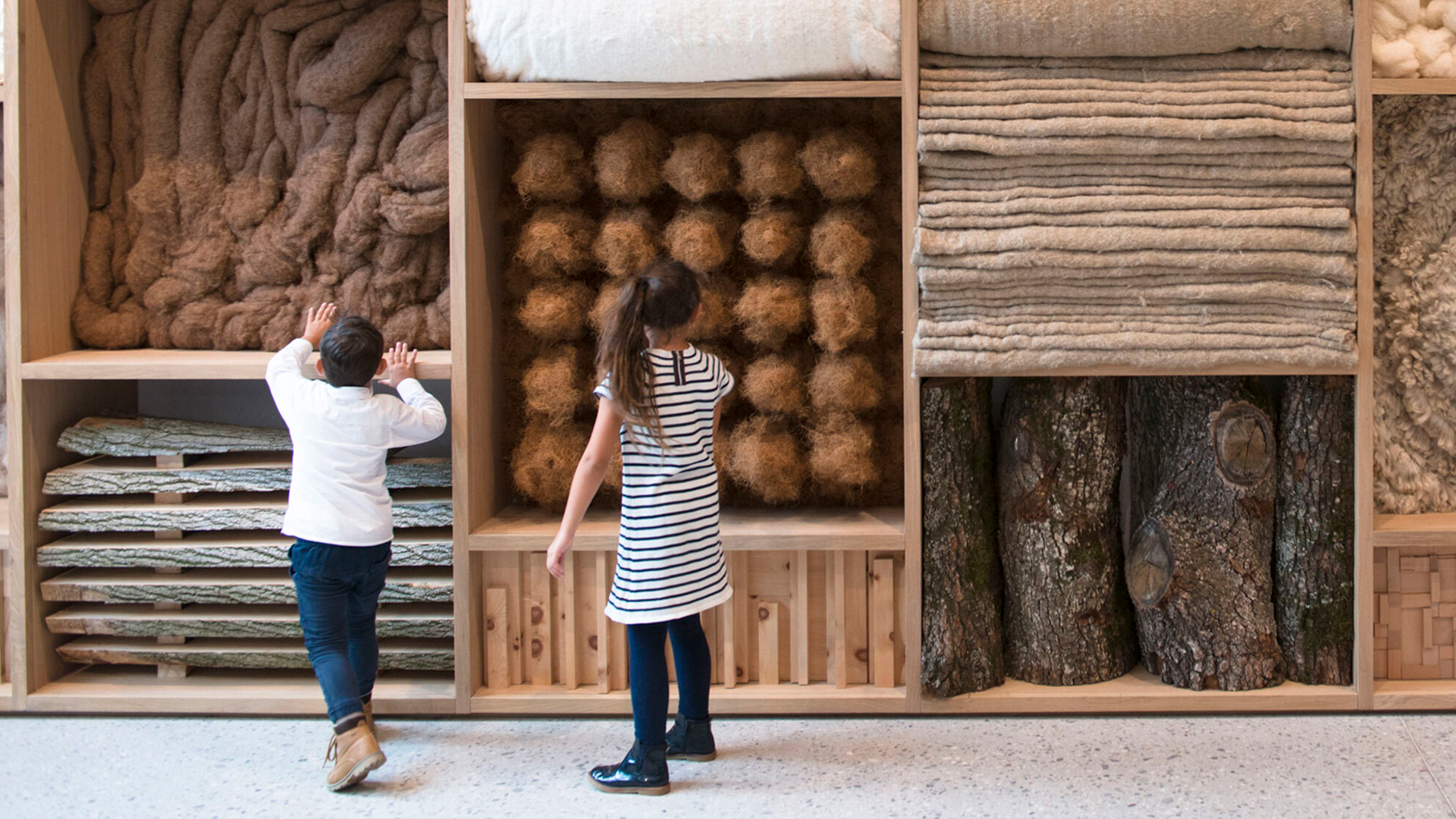Kinder stehen vor einem Holzkasten mit Naturmaterialien