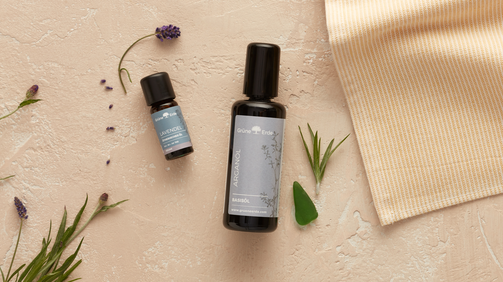 Arganöl und Lavendelöl mit Tuch und Kräutern auf hellem Hintergrund