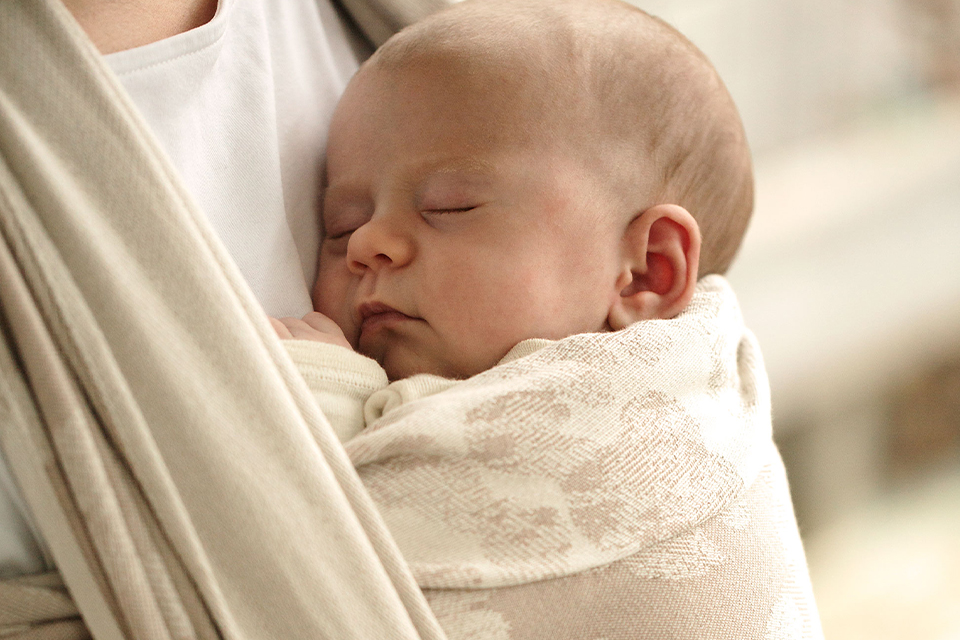 Ein Baby schläft im Tragetuch