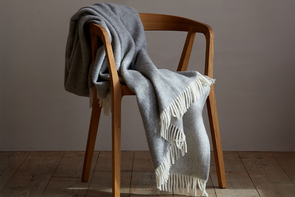Eine graue Wohndecke über einen Holzstuhl drapiert