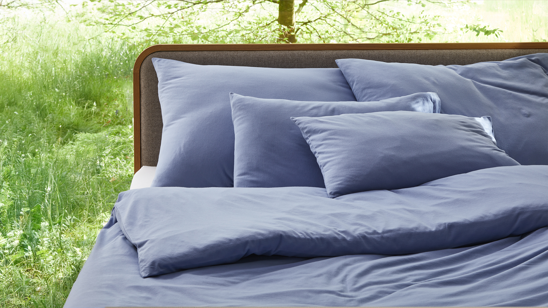 Blaue Bettwäsche auf einem Bett drapiert