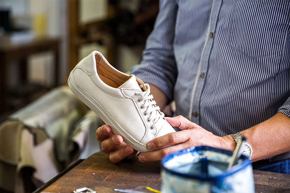 Ein Mann hält einen weißen Lederschuh in den Händen